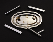 A silver-toned jewelry organizer tray with scalloped edges, surrounded by four slim silver cylindrical cases engraved with 'DR DIAMOND' on a black background. The central tray holds several pieces of gold and silver jewelry, including rings, earrings, and a chain.